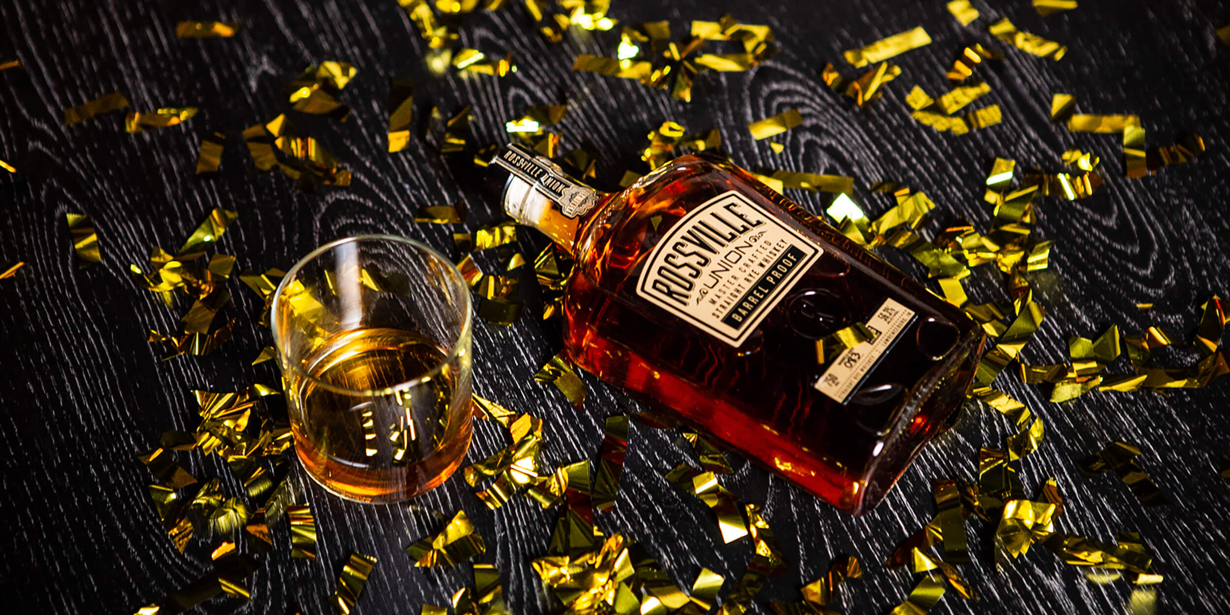 bottle of rossville and glass with gold confetti